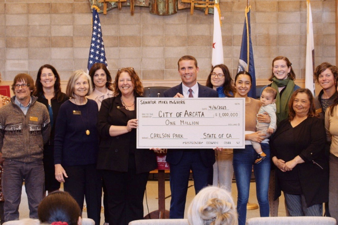 State Senator McGuire holds a big check for $1 million with Councilmembers and CUNA representatives